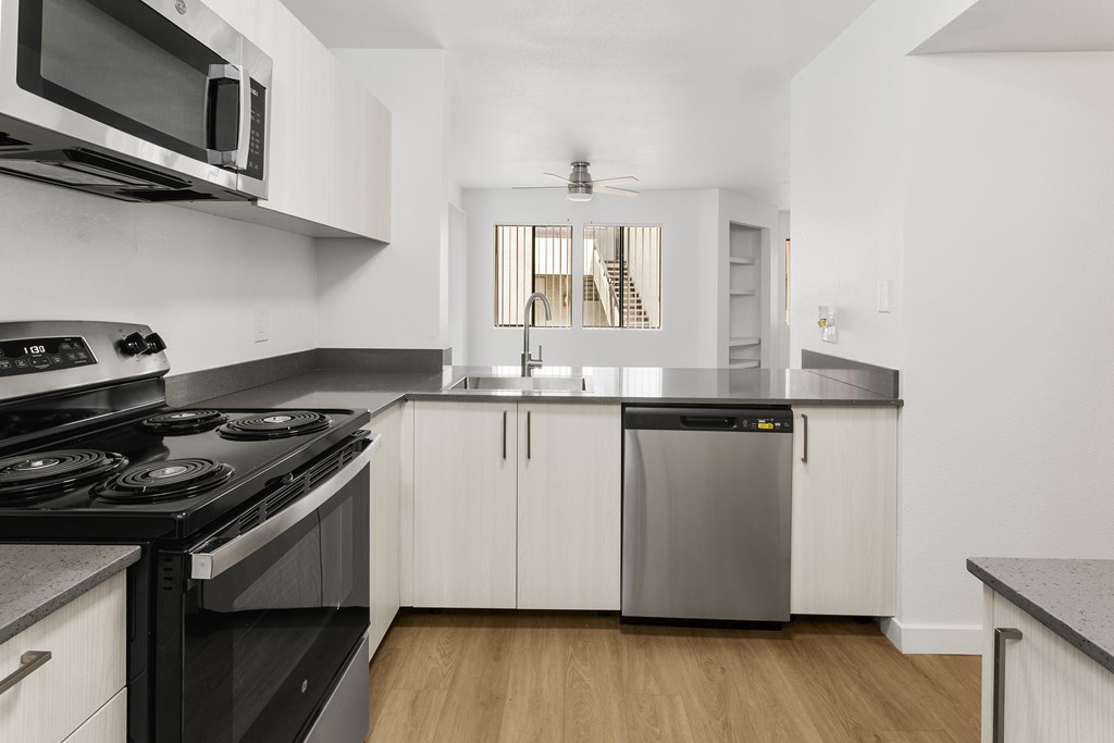 A modern kitchen with a black stove top oven and white cabinets.