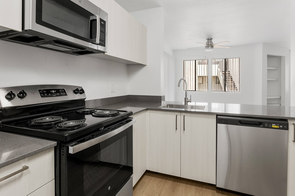 A modern kitchen with a black stove top oven and white cabinets.