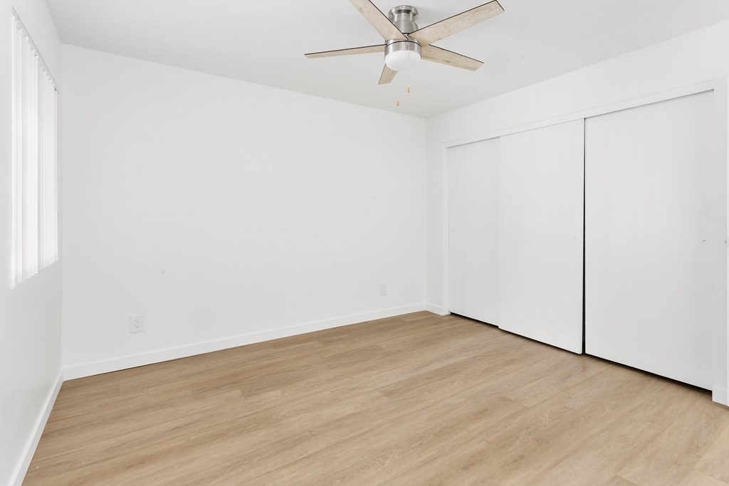 A room with a ceiling fan and wooden flooring.