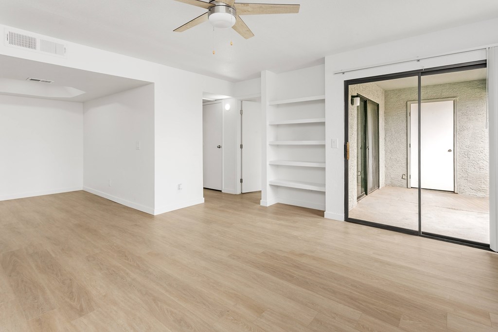 A room with a ceiling fan and sliding glass doors.