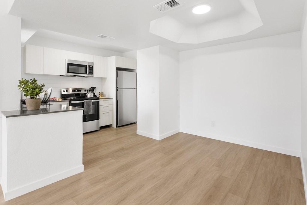 A kitchen with white cabinets and a wooden floor.