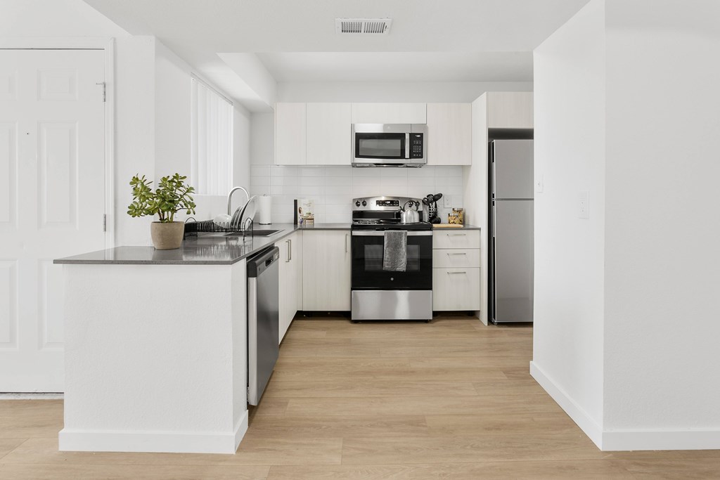 A white kitchen with a black stove top oven.