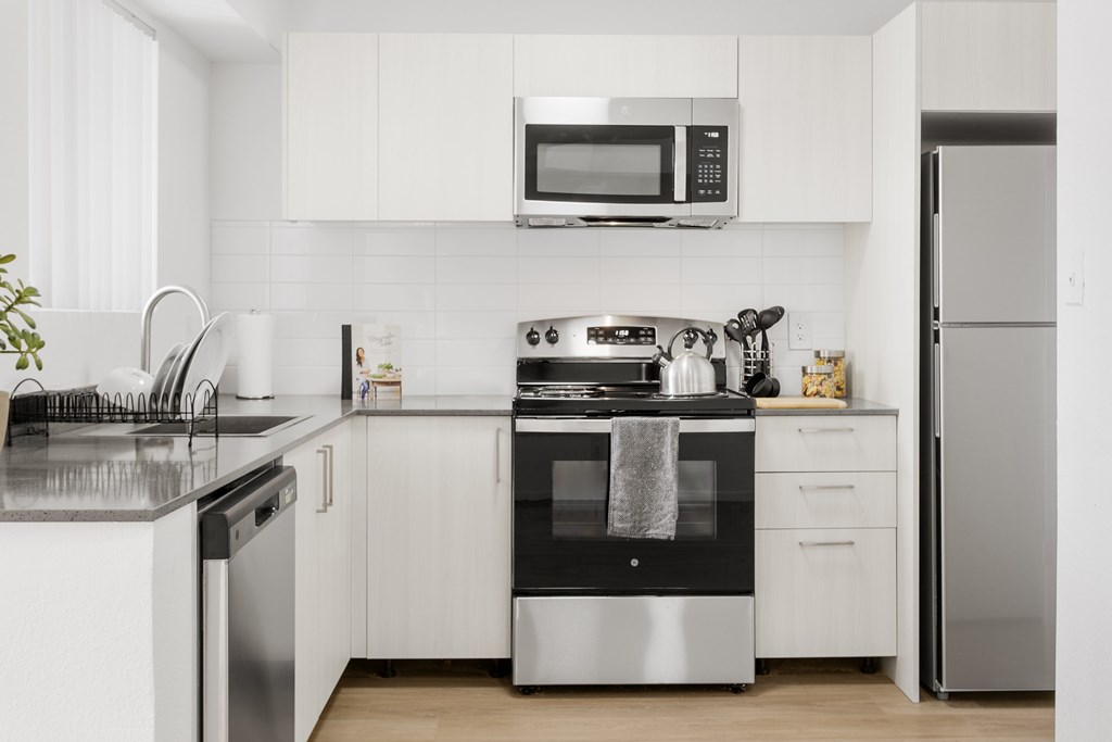 A modern kitchen with white cabinets and stainless steel appliances.