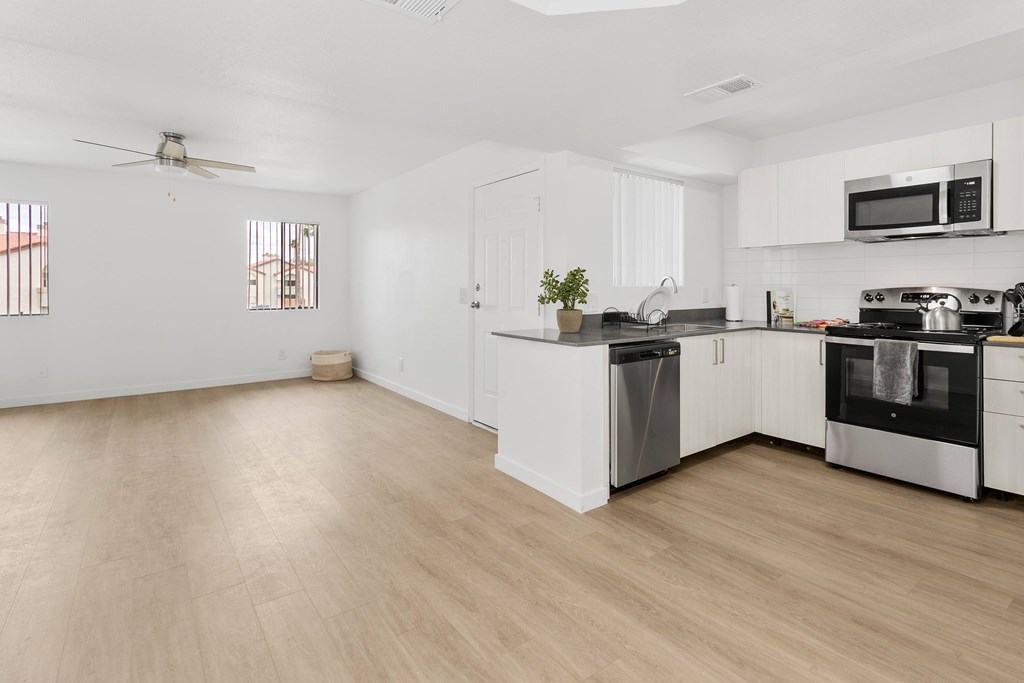 A kitchen with white cabinets and a wooden floor.