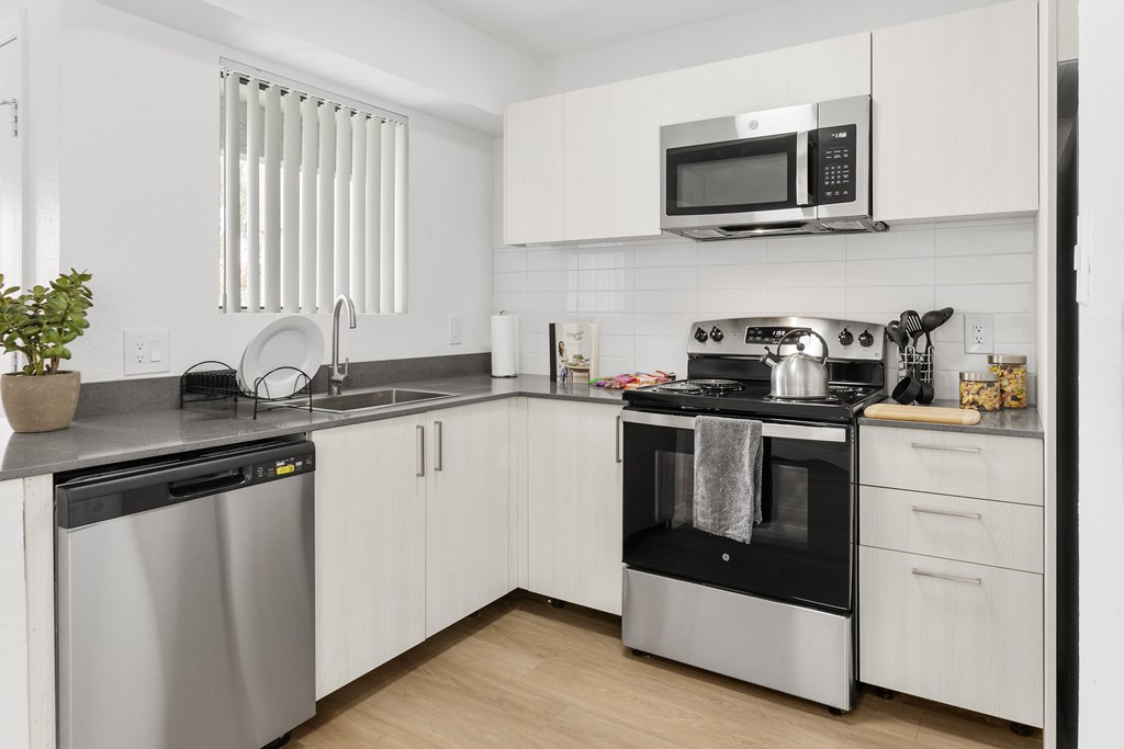 A modern kitchen with white cabinets and stainless steel appliances.