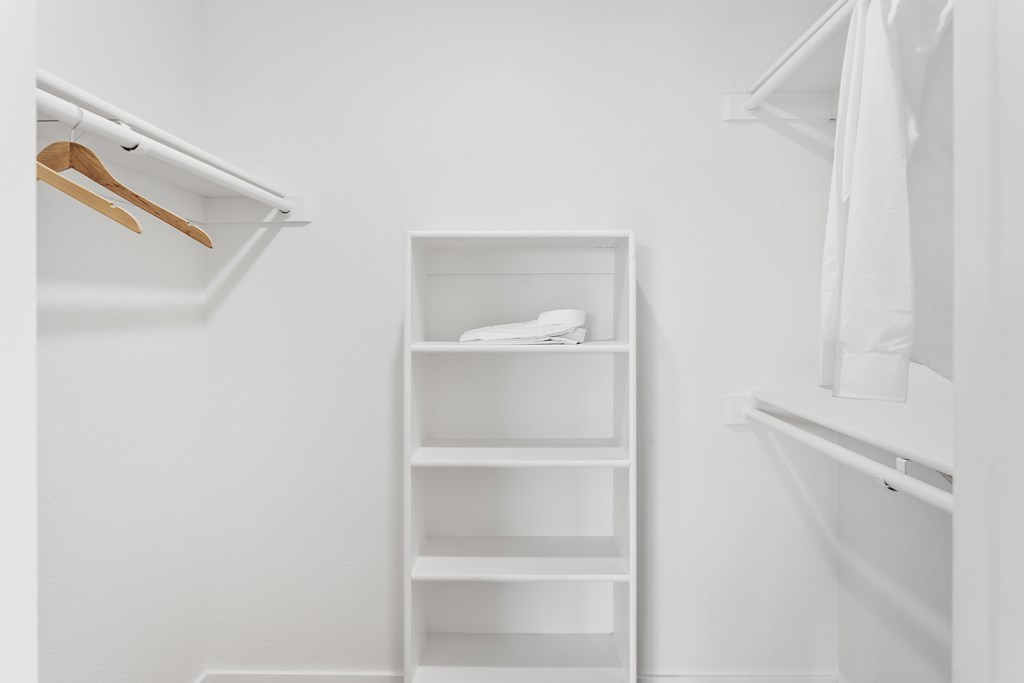 A white closet with a shelf and a hanger.