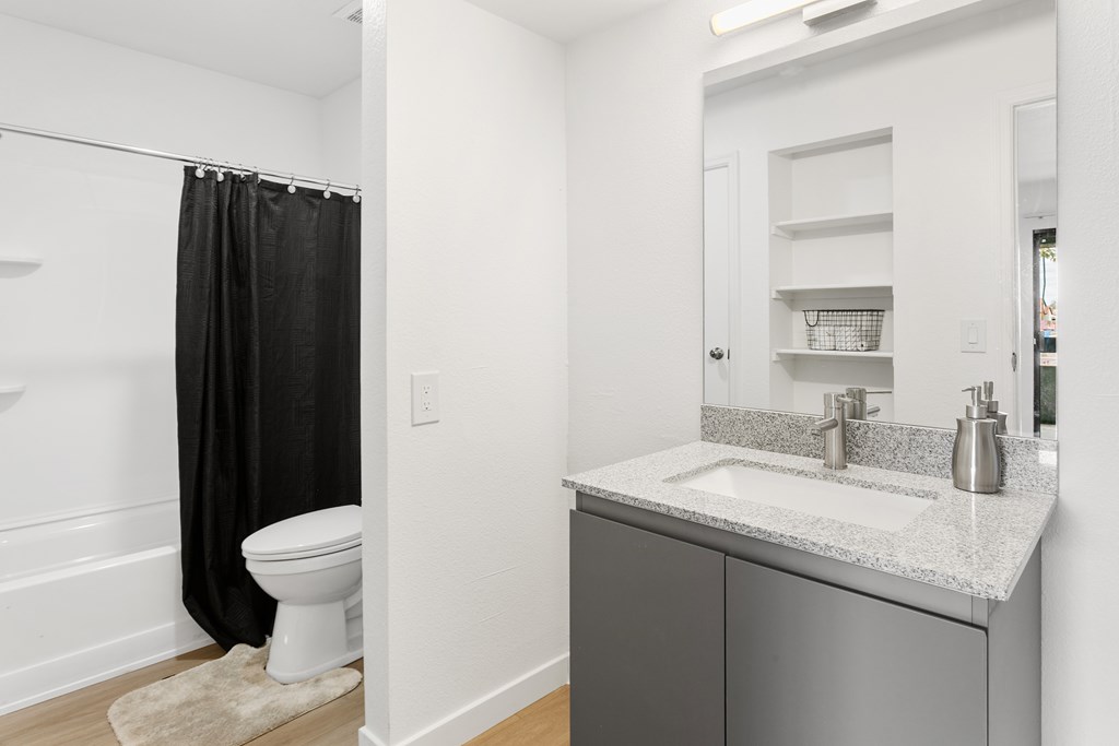 A bathroom with a white toilet and a black shower curtain.