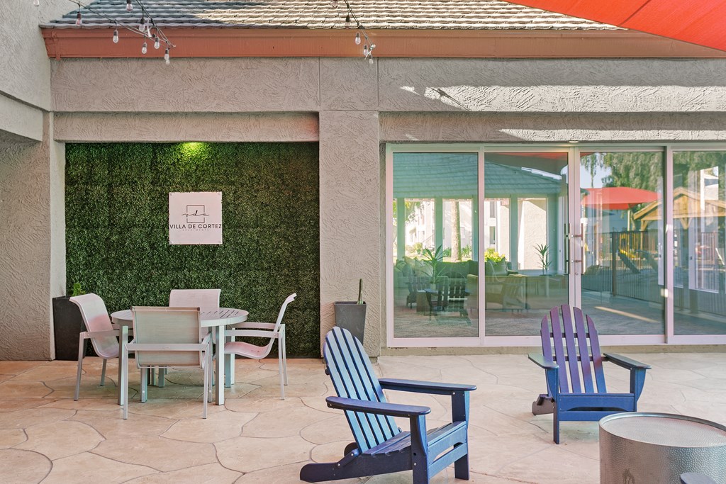 a patio with a table and chairs and a green hedge