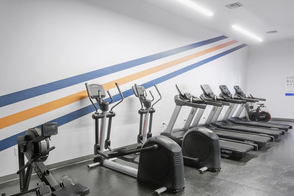 a row of exercise machines in front of a white wall with blue and yellow stripes