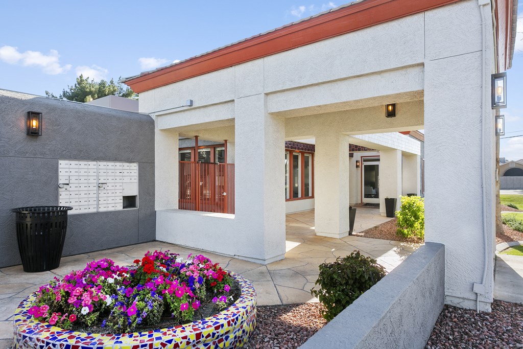a white building with a red roof and a large planter with colorful flowers