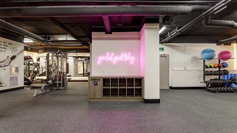 A gym with a pink neon sign that says "gymlytics".