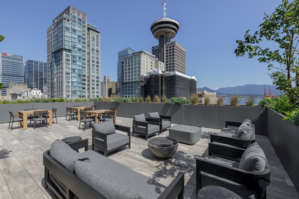A rooftop patio with a view of the city skyline and a tall tower.