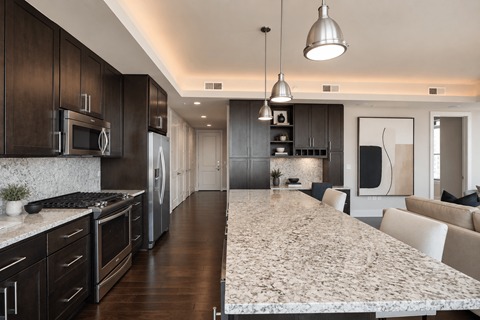 A modern kitchen with dark wood cabinets and a marble countertop.