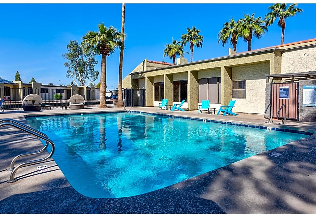 a large swimming pool in front of a building with palm trees