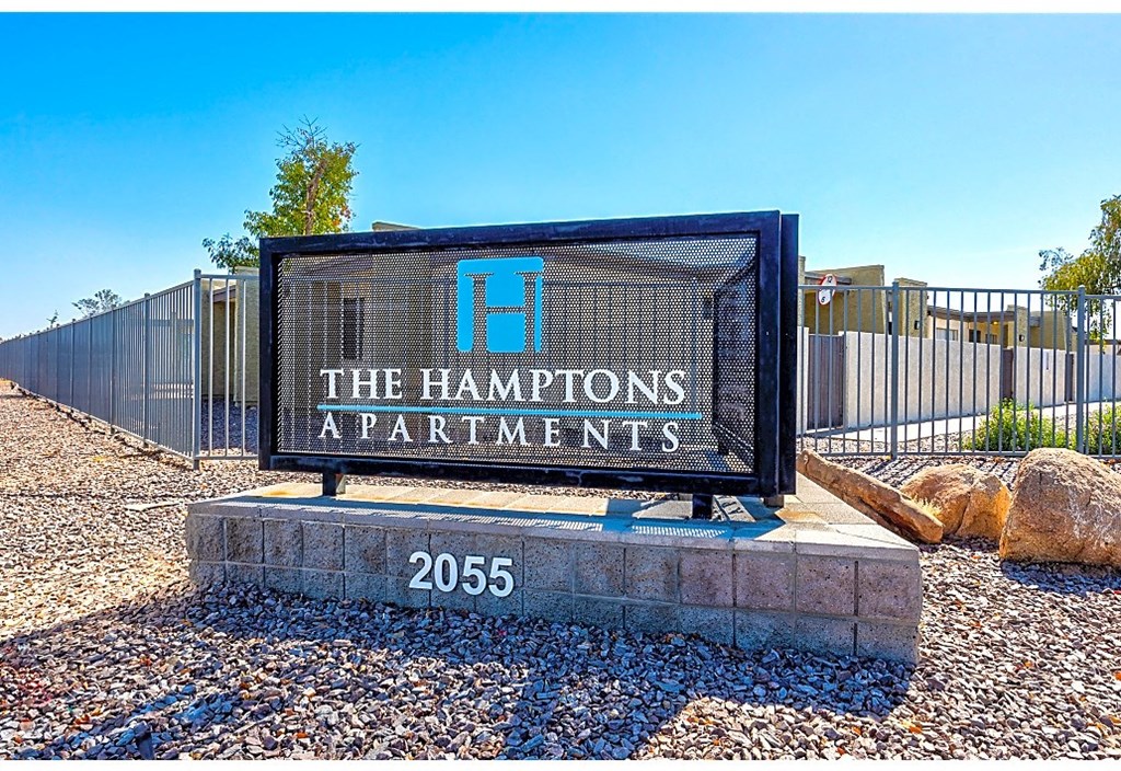 the hamptons apartments sign in front of a fence