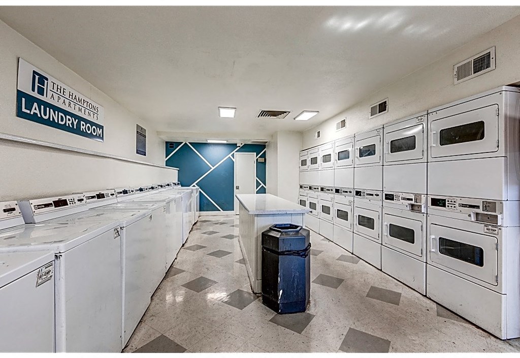 a laundry room with many white appliances and a trash can
