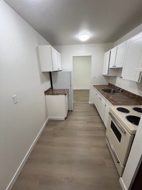 A kitchen with white cabinets and a brown countertop.