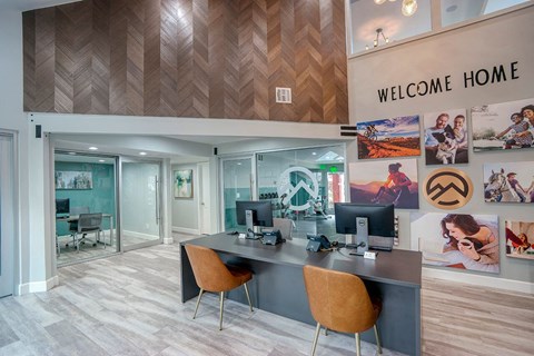 A modern office space with a wooden ceiling and a "Welcome Home" sign.