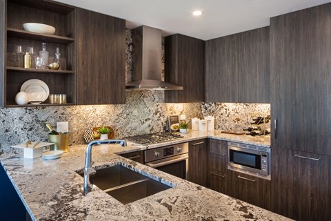 A modern kitchen with dark wood cabinets and a marble countertop.