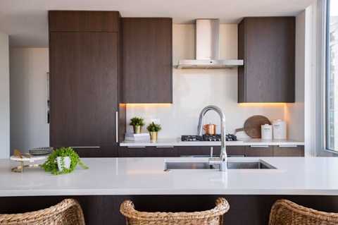 A modern kitchen with dark brown cabinets and white countertops.