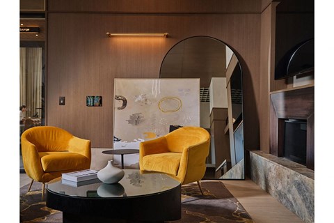 A living room with a round table and two yellow chairs.