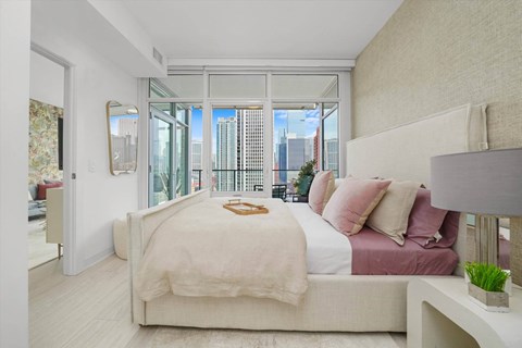 Bedroom with floor to ceiling windows and skyline views at Onni Fulton Market Apartments, Chicago, IL