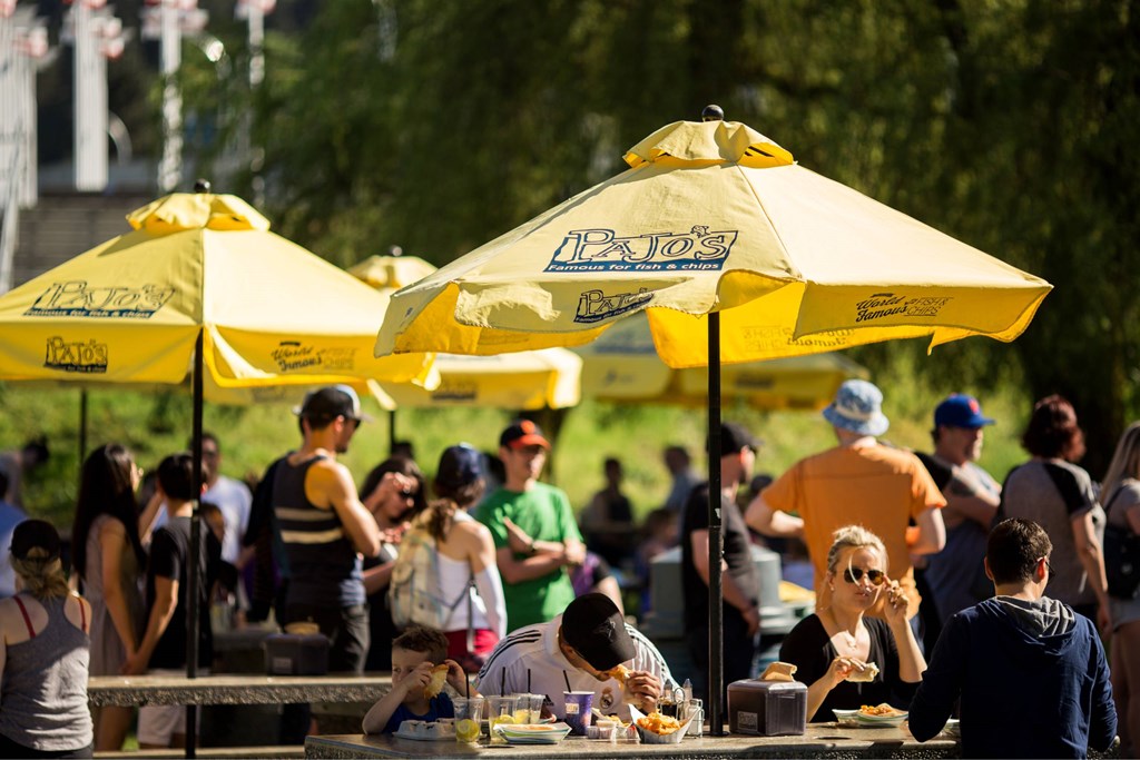 A group of people are sitting at tables under yellow umbrellas.