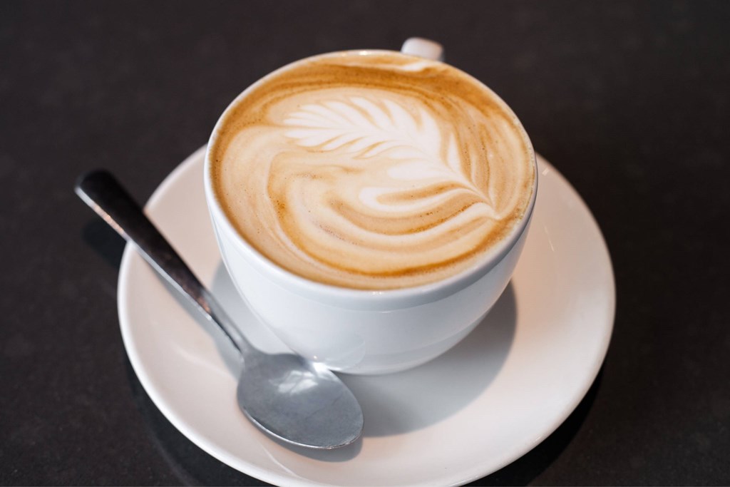A cup of coffee with a latte art design on top.