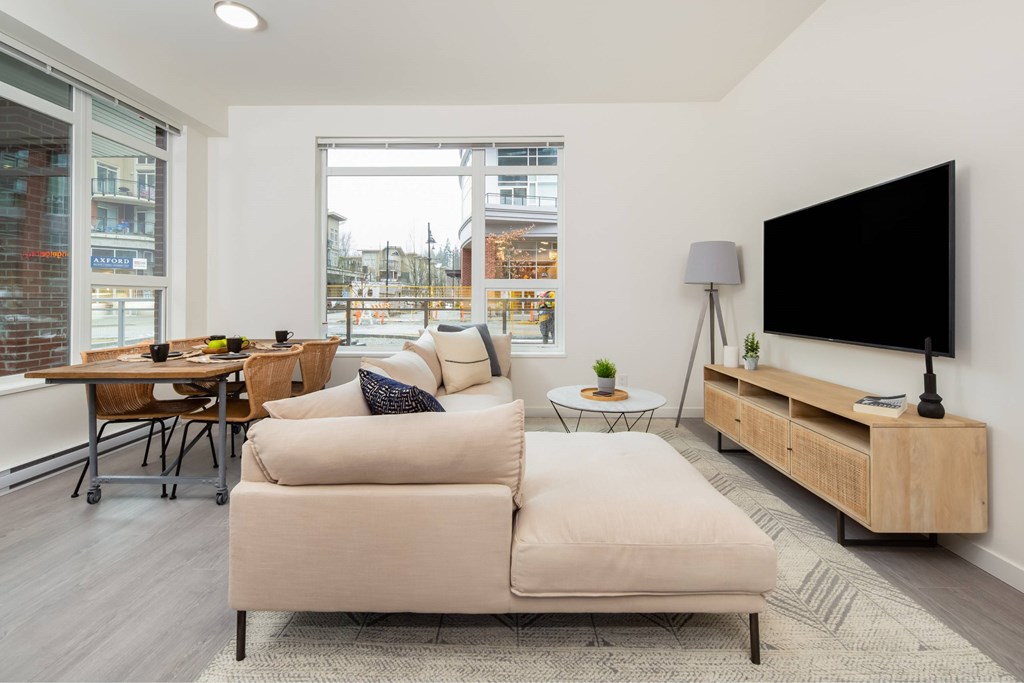 A modern living room with a large couch, a flat screen TV, and a wooden cabinet.