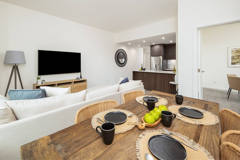 A modern dining room with a wooden table set for four.
