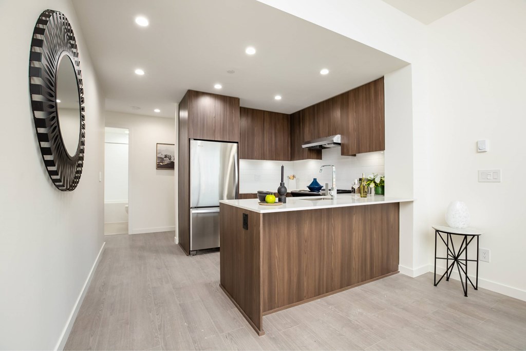A modern kitchen with wooden cabinets and a large mirror on the wall.