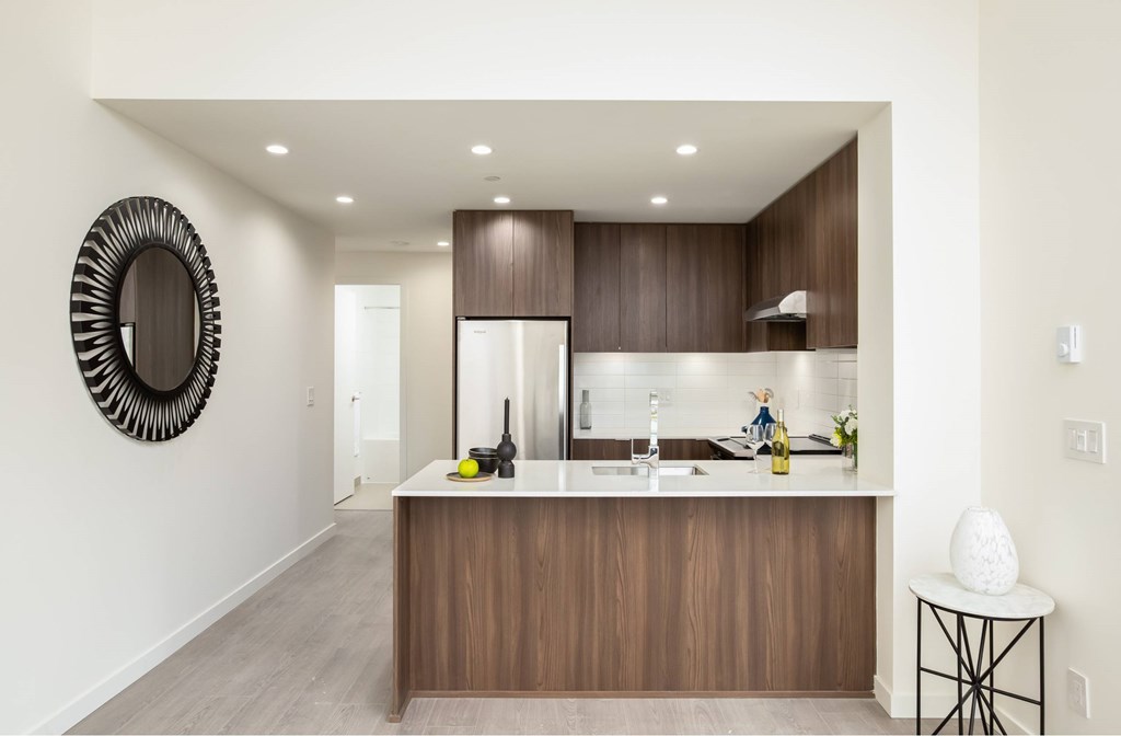 A modern kitchen with a wooden island and a large mirror on the wall.