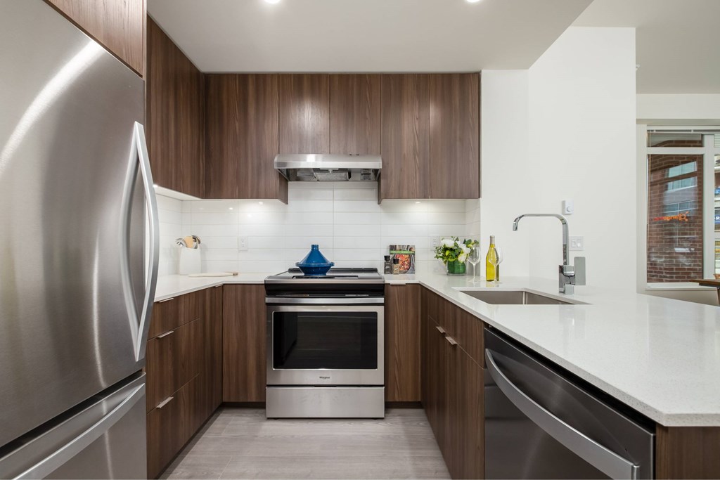 A modern kitchen with a stainless steel refrigerator and wooden cabinets.