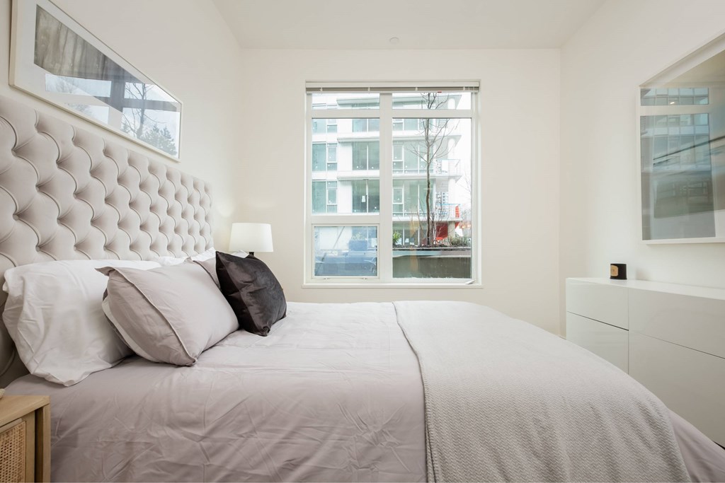 A bedroom with a large bed and a window overlooking a cityscape.