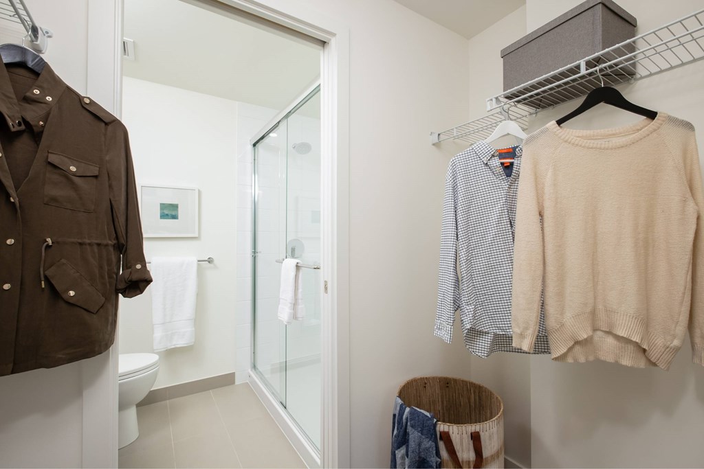 A brown jacket is hanging on a rack next to a white towel.