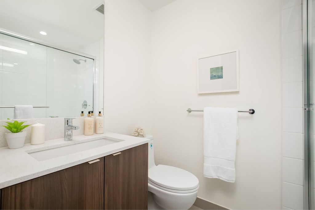 A bathroom with a toilet, sink, and a picture on the wall.