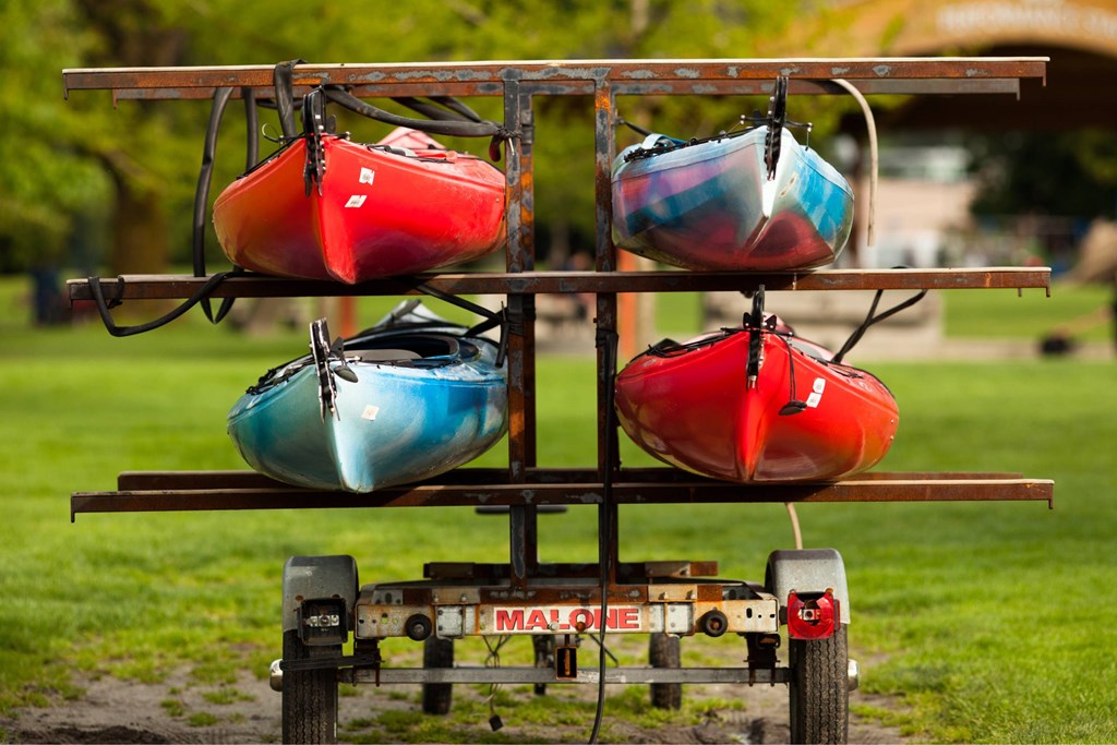 Three kayaks are stacked on a trailer.