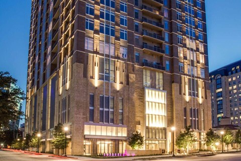 A tall building with many windows is lit up at night.