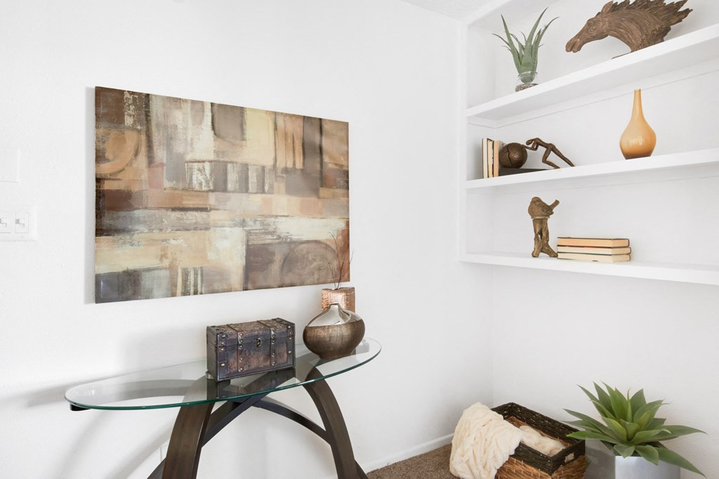a living room with a glass table and a painting on the wall