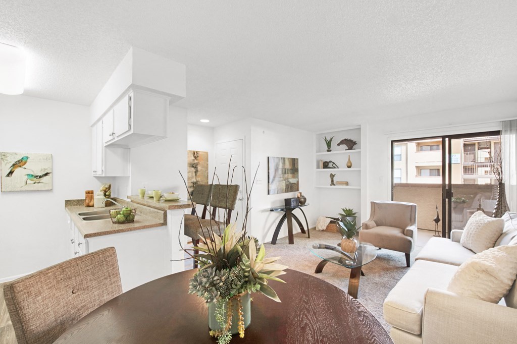 a living room with a dining table and a kitchen in the background