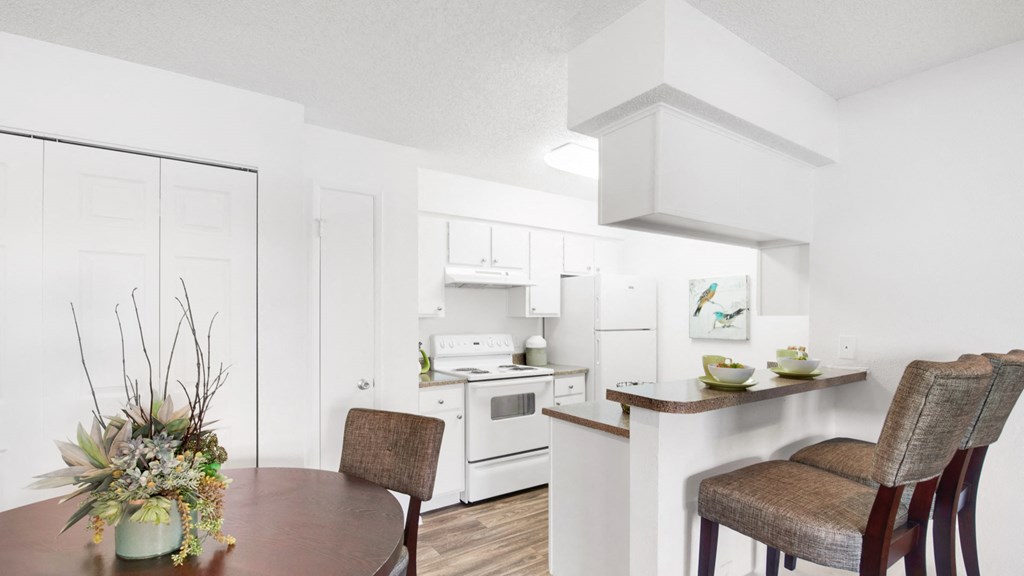 a white kitchen and dining room with a table and chairs