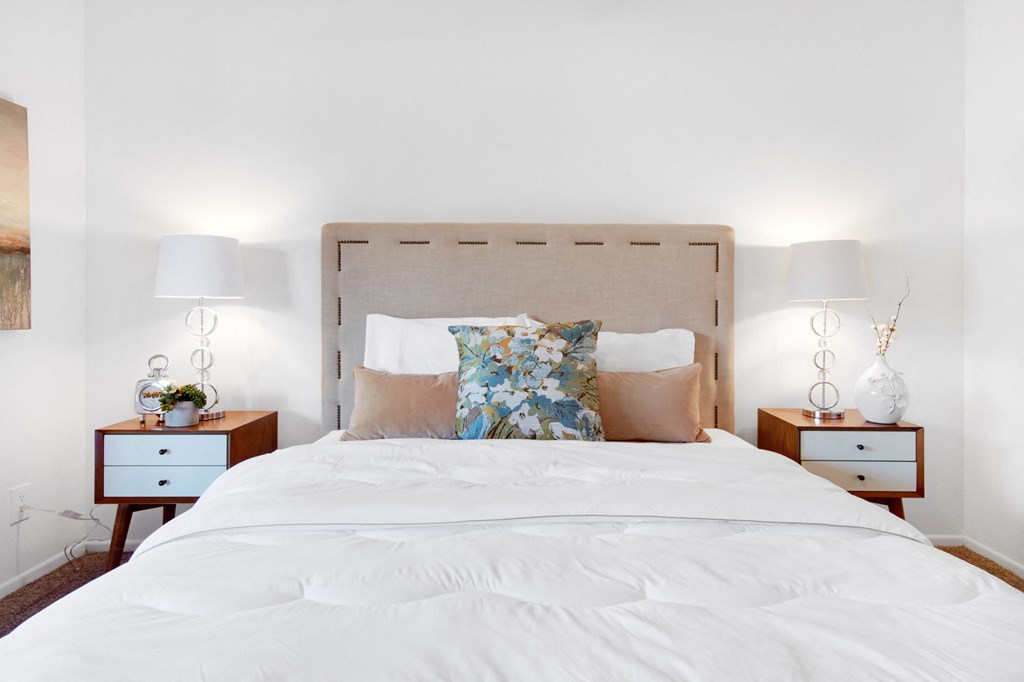 a bedroom with a bed with pillows and two nightstands with two lamps