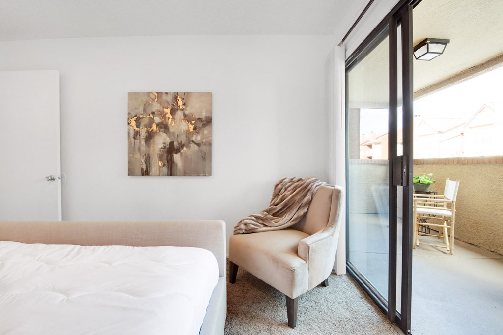 a bedroom with a bed and a chair and a sliding glass door