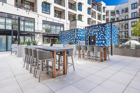 an outdoor patio with tables and chairs and a building in the background at SMB Hollywood Apartments, Apartments, Los Angeles, CA
