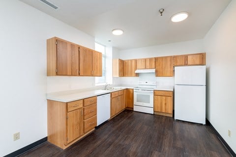 an empty kitchen with white appliances and wooden cabinets