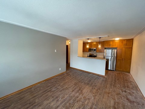 an empty living room and kitchen with wood flooring