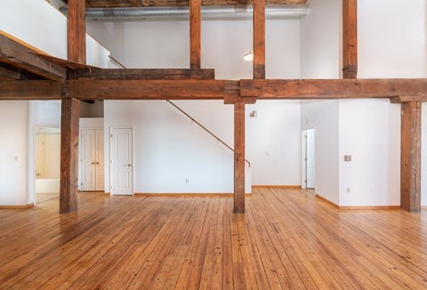 a living room with white walls and wood floors and a staircase