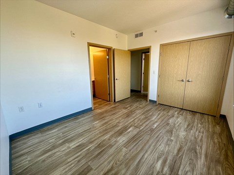 an empty living room with wood flooring and two closets