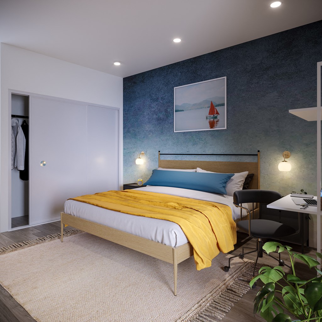 a bedroom with a bed with a yellow blanket and a blue and white painting on the wall