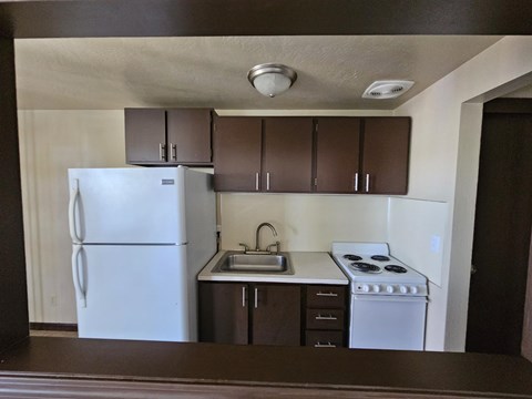 A kitchen with brown cabinets and a white refrigerator.